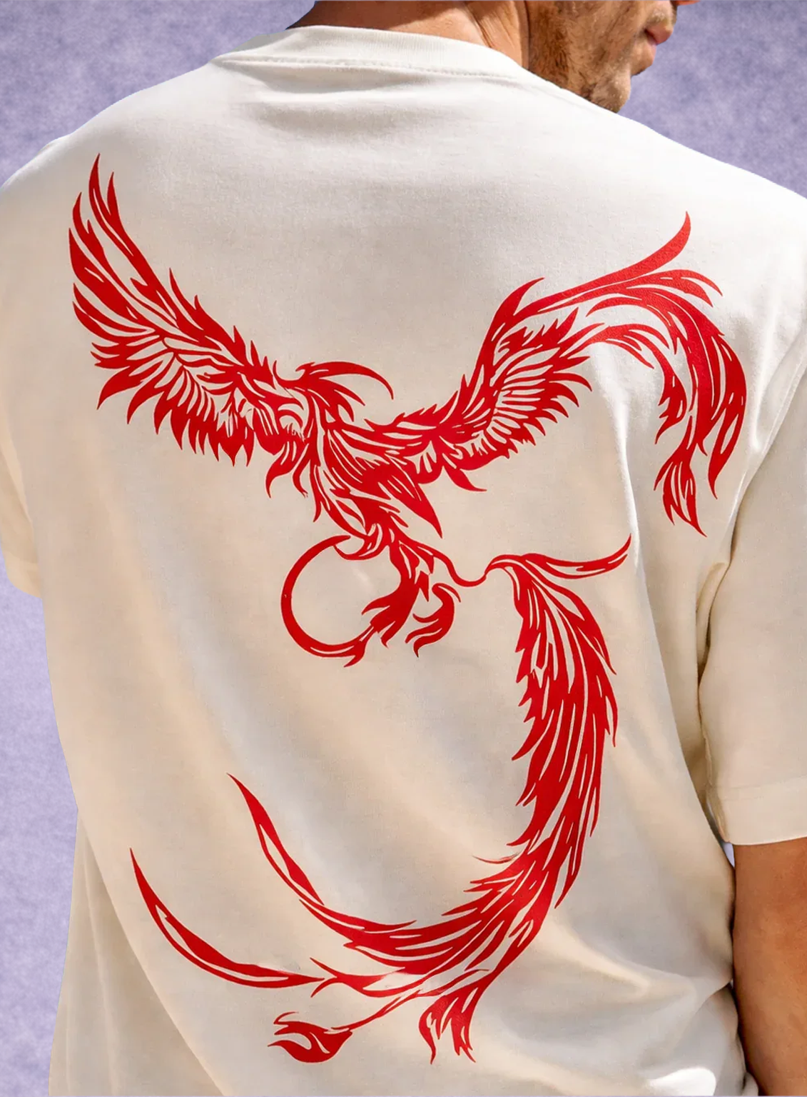 Person wearing a white shirt with a red phoenix design on the back against a light purple background
